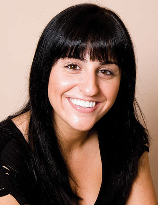 A woman with dark hair and a smile is posing for the photo.