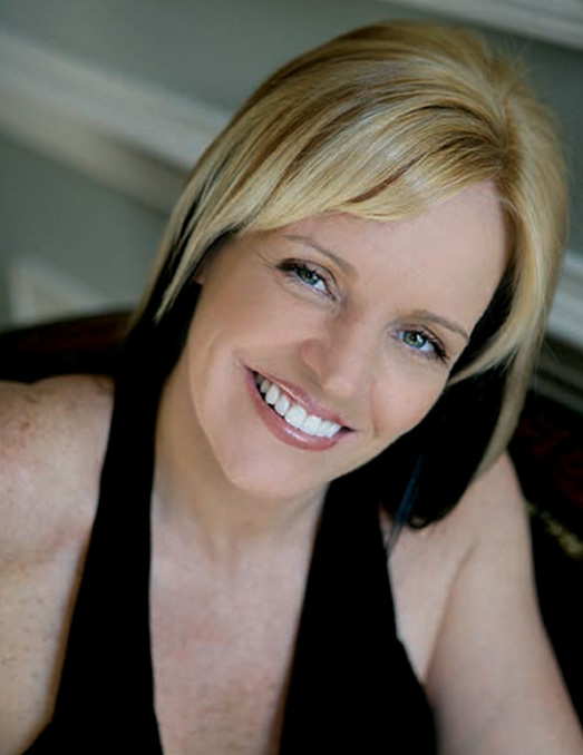 The image features a smiling woman with blonde hair, wearing a black top, posing for the photo.