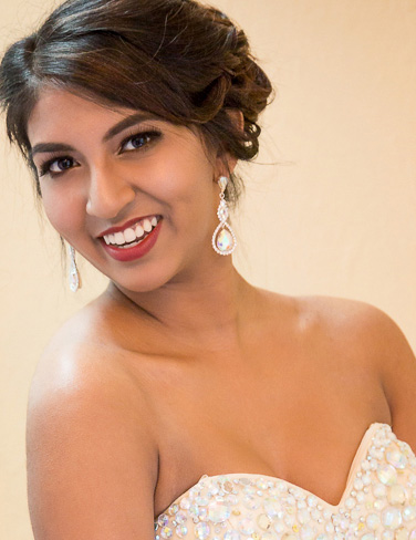 The image shows a woman wearing a strapless, white bridal gown with sequin details and a sweetheart neckline, posing for a portrait.
