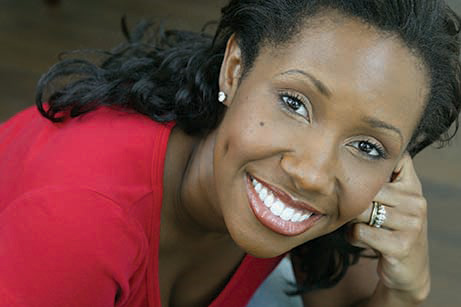 The image shows a woman with a smile, wearing a red top and posing for the camera.