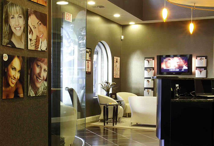 A spacious, well-lit salon featuring a reception area with a television displaying a woman s face and a large window showcasing the interior.