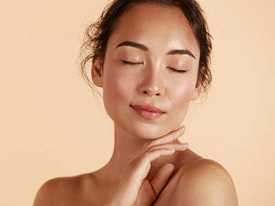 A woman with closed eyes and a serene expression, set against a soft beige background.