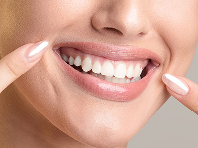 Smiling woman with well-groomed teeth, displaying a toothpaste product.