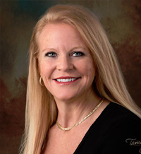 The image is a portrait of a woman in professional attire, smiling at the camera.