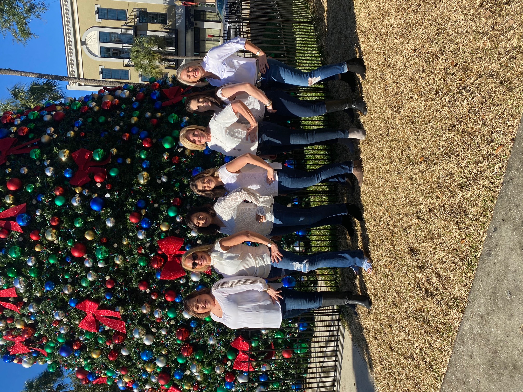 A group of people posing in front of a Christmas tree.