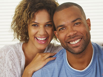 A couple, a man and a woman, are smiling at the camera.