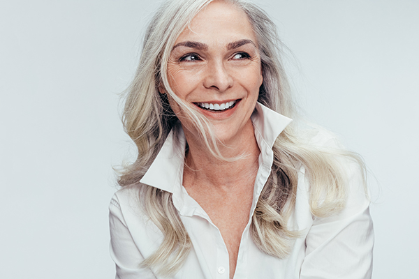 A woman with short blonde hair, wearing a white shirt and smiling broadly.