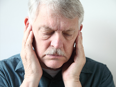 The image shows a man with his hand on his face, possibly in pain or discomfort.